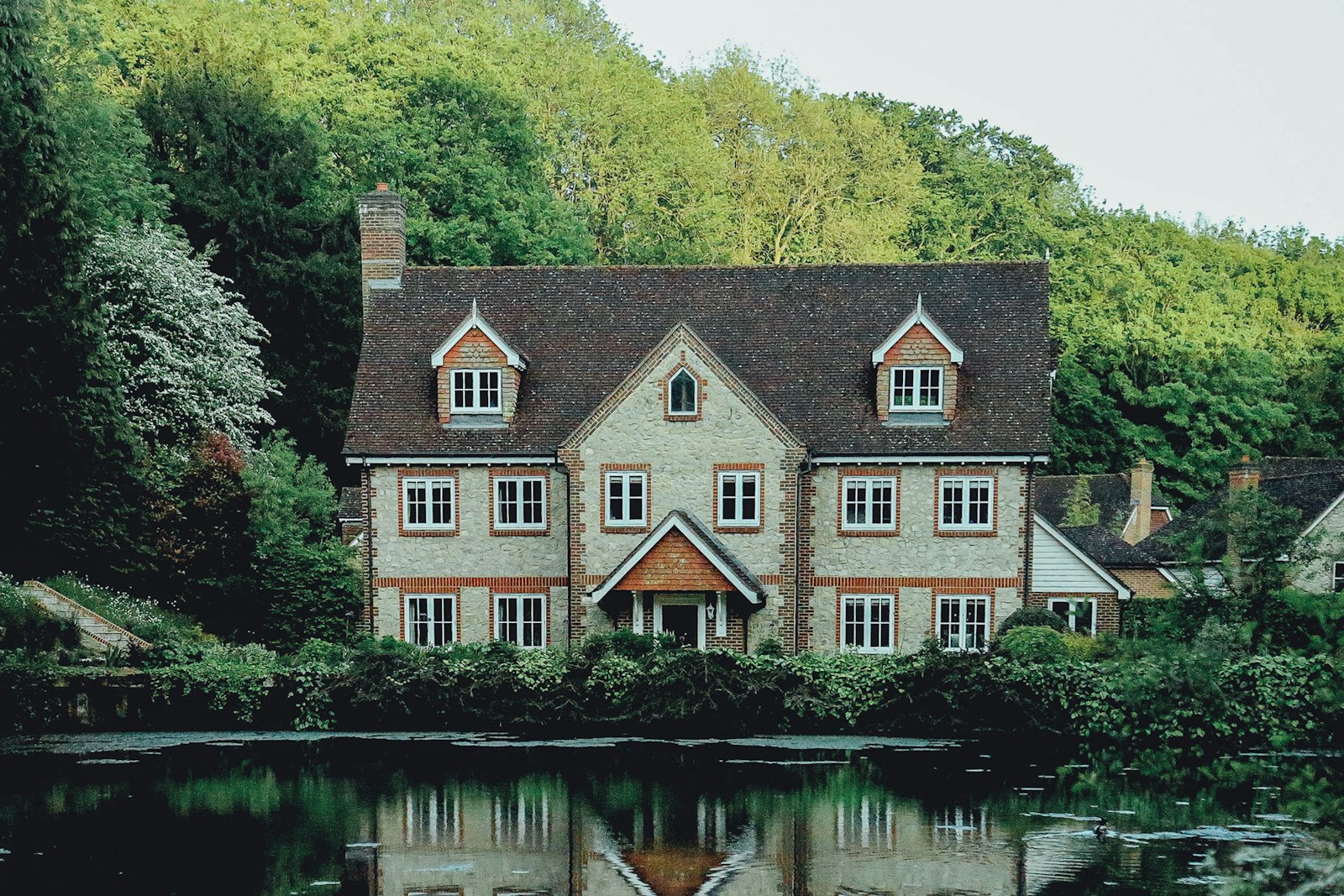 concrete house near a body of water and forest, home insurance